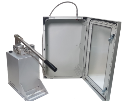 a polycarbonate test enclosure next to a hydraulic hand pump set with a hose going between them