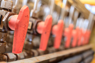 a swagelok ball valve shown in clarity, with more valve handles shown blurry as they stretch off into the distance behind the valve in focus