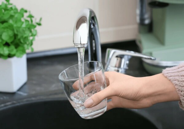 high quality potable water from the tap HQ Hand holding a glass under a running tap filling it with clear and fresh drinking water.