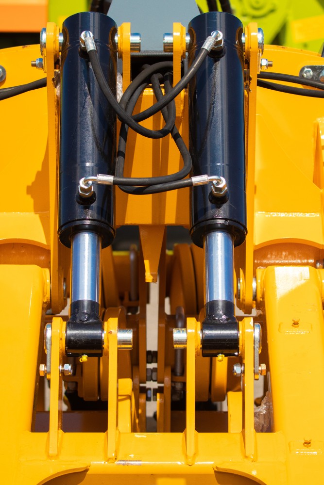 two hydraulic cylinders side by side, connected with hoses